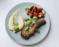 Fillet steak with mashed potatoes and fresh vegetable salad on a blue plate over white background Royalty Free Stock Photo