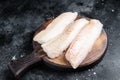 Fillets of codfish, raw cod fish meat. Black background. Top view