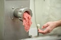 Filling comes out through raw meat grinder sieve. Grinder closeup. Electric mincer machine with fresh chopped meat. Process of