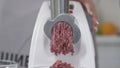 Filling comes out through raw meat grinder sieve. Grinder closeup. Electric mincer machine with fresh chopped meat