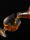 Filling a glass of brandy on a black background. Royalty Free Stock Photo