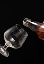 Filling a glass of brandy on a black background. Royalty Free Stock Photo