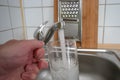 Filling a glass with tap water for drinking by holding it in man hand at the sink in the kitchen Royalty Free Stock Photo