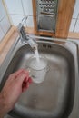 Filling a glass with tap water for drinking by holding it in man hand at the sink in the kitchen Royalty Free Stock Photo