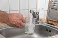 Filling a glass with tap water for drinking by holding it in man hand at the sink in the kitchen Royalty Free Stock Photo