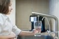 Filling glass with tap water. Modern faucet and sink in home kitchen. Child is pouring fresh drink to cup. Healthy lifestyle. Royalty Free Stock Photo