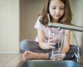 Filling glass with tap water. Modern faucet and sink in home kitchen. Child is pouring fresh drink to cup. Healthy lifestyle. Royalty Free Stock Photo