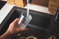 Filling glass of water from stainless steel kitchen faucet. Drinking water concept Royalty Free Stock Photo