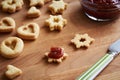 Filling homemade Linzer Christmas cookies with red jam