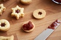 Filling homemade Linzer Christmas cookies with red jam