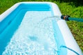 Filling the inflatable pool with water. Swimming pool in the summer garden. Royalty Free Stock Photo