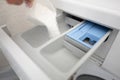 Filling the laundry compartment of the washing machine with white powder to clean the laundry