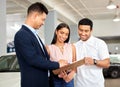 After filling this out, you can take your new car home. a car salesman assisting a young couple on the showroom floor. Royalty Free Stock Photo