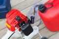 filling up with fuel from a red canister with gasoline, manual lawn mower close-up, on a wooden background