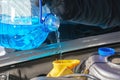 Filling a windshield washer tank of a car with a wiper fluid outdoors