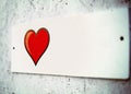 Film effect, film grain. a small white plaque on the wall of pressed plywood. beautiful red heart with black edging, Billboard