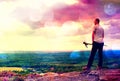 Film grain. Adult hiker with poles in hand. Hiker take a rest on rocky view point above valley. Royalty Free Stock Photo