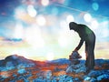 Film grain effect. Alone adult man is stocking stone to pyramid. Alps mountain summit, Royalty Free Stock Photo