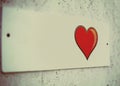 film grain. a small white plaque on the wall of pressed plywood. beautiful red heart with black edging, Billboard