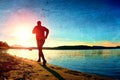 Film grain. Sportsman running at amazing summer sunset along coastline in sport and healthy possitive lifestyle concept Royalty Free Stock Photo