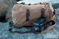 The film medium format camera lies on the stones against the backdrop of a canvas vintage backpack