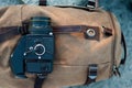 The film medium format camera lies on the stones against the backdrop of a canvas vintage backpack