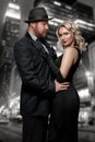 Film noir. Detective man in a raincoat and hat and a dangerous woman with red lips in black dress. Couple stands against