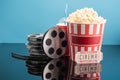 film reels, cup of soda, cinema ticket and bucket of popcorn on glossy surface isolated on blue. Royalty Free Stock Photo