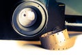 Film strips closeup with vintage movie cinema camera with lens on background Royalty Free Stock Photo