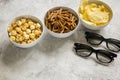 film whatching party with glasses, crumbs, chips and pop corn stone background