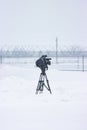 A filming camera on tripod standing on the snowy airfield