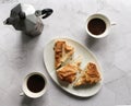 Breakfast. Filo pastry cake on a white plate. geyser coffee maker, coffee cups on a marble table