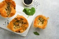Filo pies with soft feta cheese and spinach in ceramic molds on old grey table background. Filo portions pies. Small Baked