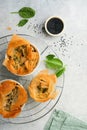 Filo pies with soft feta cheese and spinach in ceramic molds on old grey table background. Filo portions pies. Small Baked