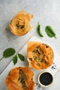 Filo pies with soft feta cheese and spinach in ceramic molds on old grey table background. Filo portions pies. Small Baked