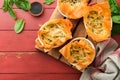 Filo pies with soft feta cheese and spinach in ceramic molds on old red wooden table backgrounds. Filo portions pies. Small Baked