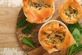 Filo pies with soft feta cheese and spinach in ceramic molds on old wooden table background. Filo portions pies. Small Baked