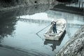 Filtered image woman worker on the boat cleaning up a polluted river in Hanoi, Vietnam Royalty Free Stock Photo