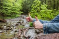 Fimale traveler showing thumb up against the backdrop of nature. Tourism concept. Copyspace. Mountain river