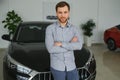 Final decision. Shot of a handsome young man standing in front of a new car at the dealership thinking rubbing his chin Royalty Free Stock Photo