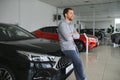 Final decision. Shot of a handsome young man standing in front of a new car at the dealership thinking rubbing his chin Royalty Free Stock Photo