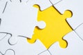 Final missing white piece lies on jigsaw puzzle on yellow background