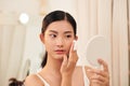 Final touches. Side view of beautiful young woman using cotton disk and looking at her reflection in mirror while sitting at the Royalty Free Stock Photo