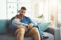 Finally hes fast asleep. a tired little boy sleeping in his fathers arms while being seated on a sofa at home during the