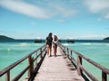 We are finally on holiday. Shot of a carefree young couple walking on a jetty together next to the ocean during the day.