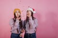 Finally holiday time. Giving air kiss using confetti. Two sisters twins standing and posing in the studio with white Royalty Free Stock Photo