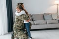 Finally meet each other. Soldier in uniform is at home with his little daughter