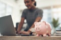 Finance, banking and saving money with piggybank, investing and planning while working on a laptop in an office at work Royalty Free Stock Photo