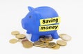 On the table are coins and a blue piggy bank with the inscription - SAVING MONEY Royalty Free Stock Photo
