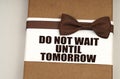 On the packing box with a bow-tie the inscription - Do Not Wait Until Tomorrow